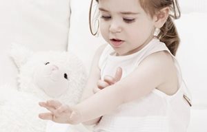 Una niña jugando con un peluche.